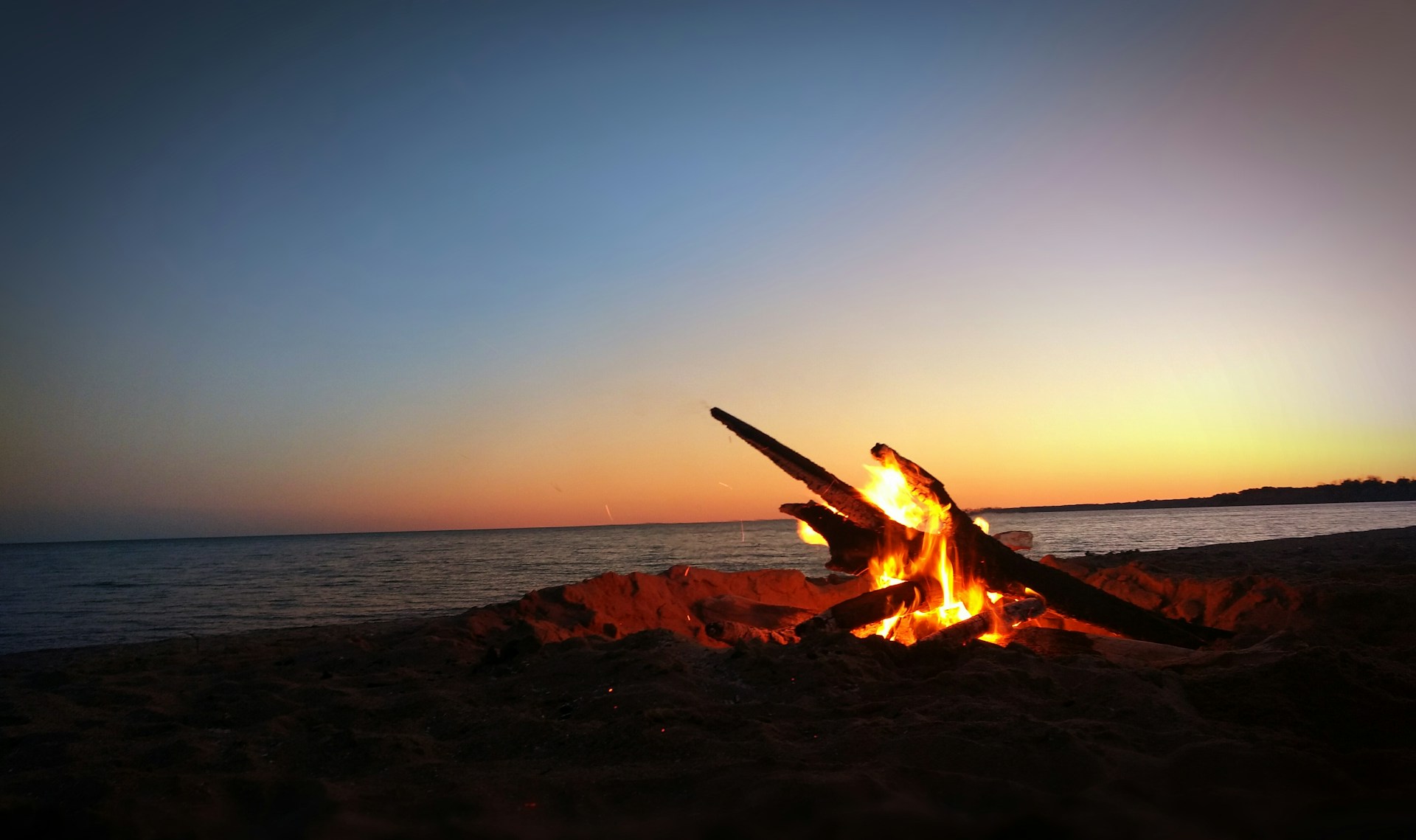 People gathered around a campfire with open sky on the horizon